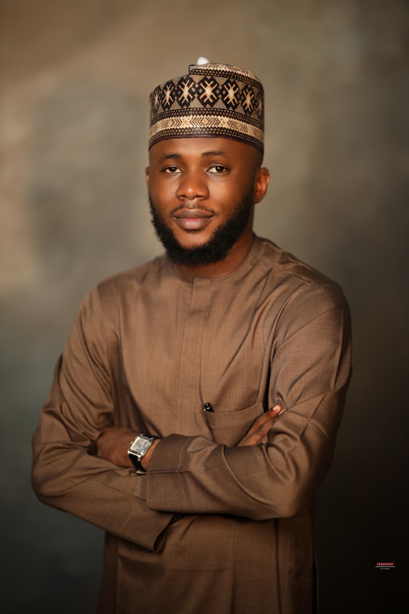 Al-Amin Idris, arms crossed, in a brown kaftan and embroidered cap
